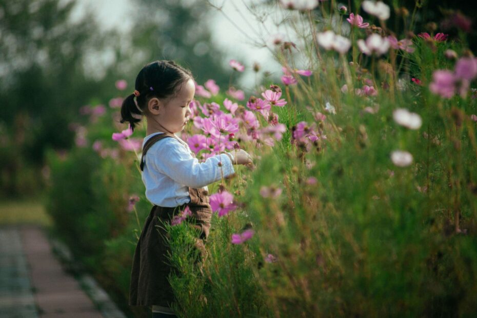 Dziewczynka w ogrodzie pełnym kwiatów.
